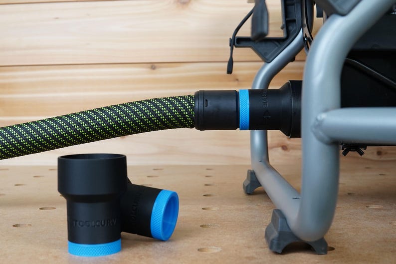 May include: A black and green hose with a blue and black connector attached to a silver metal frame. Two black and blue plastic connectors are on a wooden surface.