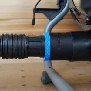 May include: Close-up of a black vacuum hose attachment with a blue ring and the text "VOLCURVE" printed on the side.