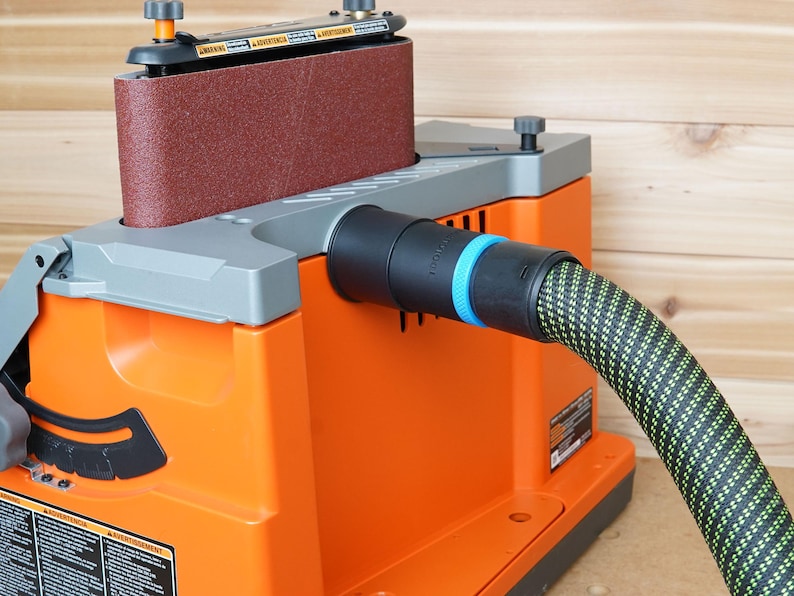 May include: Orange and gray belt sander with a black dust collection port and a green and black dust hose attached.