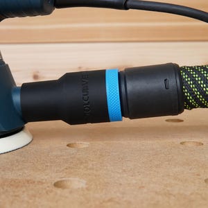 Peut inclure: Une ponceuse &eacute;lectrique bleue et noire avec un tuyau d'aspiration des poussi&egrave;res. Le tuyau est noir avec un rev&ecirc;tement en tissu &agrave; motifs vert et jaune. La ponceuse a un port d'aspiration des poussi&egrave;res bleu et noir avec le mot "ROL-CURVE" imprim&eacute; dessus.