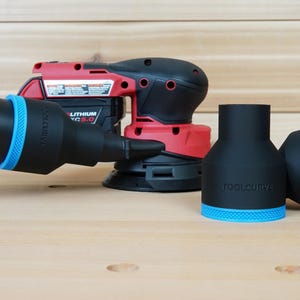 Puede incluir: Una lijadora inalámbrica roja y negra con una manguera negra y adaptadores negros con detalles azules. Los adaptadores están etiquetados como "TOOLCURVE". La lijadora tiene una batería negra.
