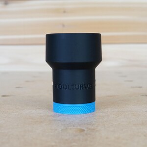 Op de afbeelding: Een zwart gereedschap met een blauwe ring aan de onderkant. Het gereedschap heeft de tekst "TOOLCURVE" aan de zijkant.