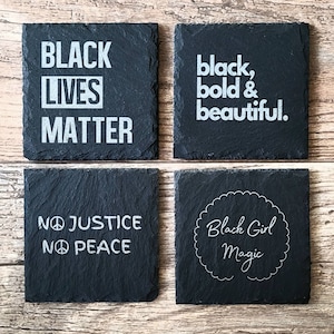 Puede incluir: Cuatro posavasos cuadrados de pizarra negra con texto blanco. Los posavasos muestran las frases "Black Lives Matter", "black, bold & beautiful", "No Justice No Peace" y "Black Girl Magic".