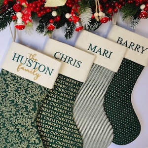 May include: Four Christmas stockings with green and white patterns. The stockings are personalised with the names "Barry", "Mari", "Chris", and "The Huston Family".