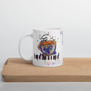 May include: White ceramic mug featuring a colourful illustration of a teacup with steam rising from it. The text "A cup of Chat is a cup of PositiviTEA" is printed on the mug.