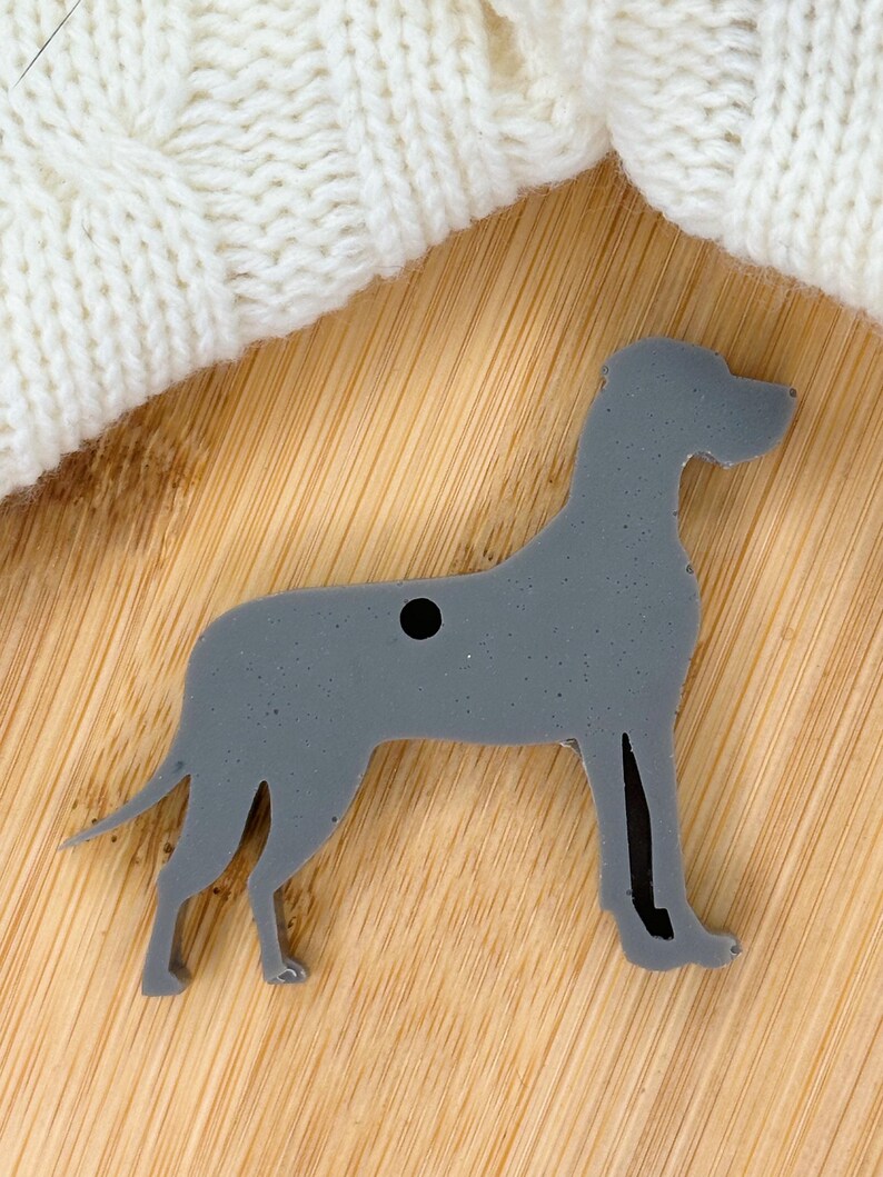 May include: A gray Great Dane dog silhouette ornament with a hole for hanging.