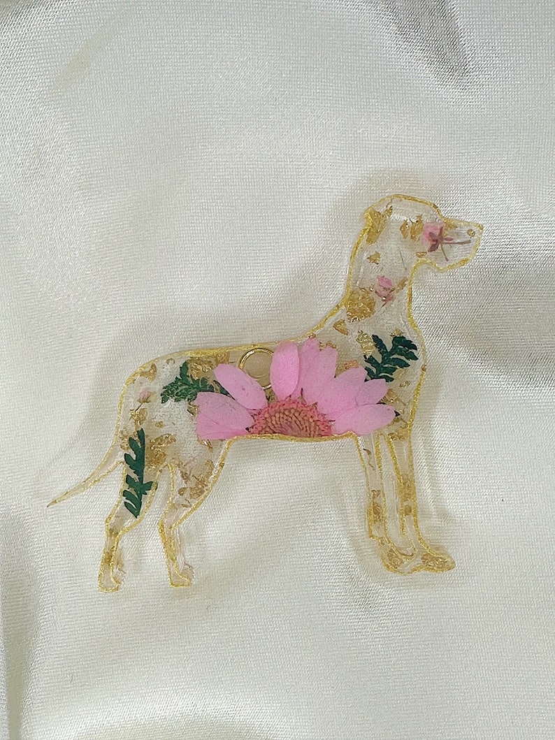 May include: A gold-coloured resin dog silhouette with a pink flower and gold leaf accents.