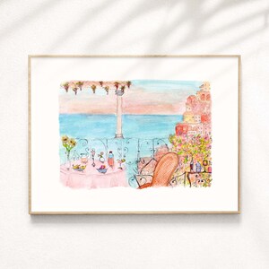 May include: Watercolor painting of a balcony overlooking the ocean with a table set for a meal. The table has a pink tablecloth and is set with glasses, plates, and a bowl of fruit. A chair is positioned at the table, facing the ocean. The background features a cityscape with buildings in shades of pink and orange.