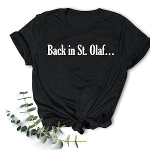 May include: Black t-shirt with white text that reads "Back in St. Olaf..."