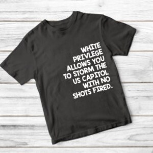May include: Black t-shirt with white text that reads "White Privilege Allows You To Storm The US Capitol With No Shots Fired."