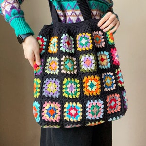 May include: A black crochet tote bag with colorful granny squares. The bag has two black straps.