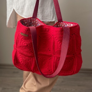 Peut inclure: Un sac fourre-tout en crochet rouge avec des anses en cuir bordeaux. Le sac est doublé de tissu floral et est assez grand pour transporter les essentiels du quotidien.