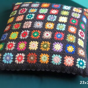 May include: A black crocheted pillow with a colorful granny square pattern. The pillow is 23x23 inches.