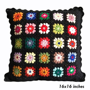 May include: A black crochet pillow with a colorful floral pattern. The pillow is 16x16 inches.