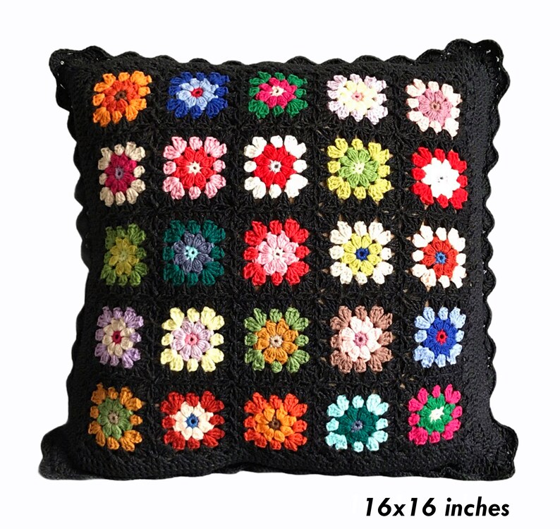 May include: A black crochet pillow with a colorful floral pattern. The pillow is 16x16 inches.