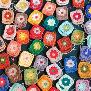 May include: A collection of colorful crocheted squares with various floral patterns. The squares are arranged in a semi-circle on a green background.