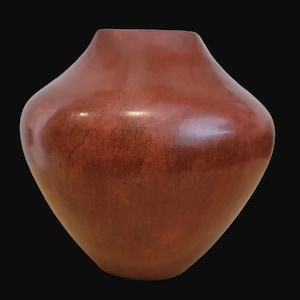 May include: A smooth, rounded vase with a wide, bulbous body that tapers toward a narrow, open top. The surface features a deep, earthy reddish-brown color with subtle, mottled variations in tone and a soft, matte finish throughout the exterior.