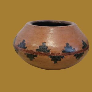 May include: A round, terracotta-colored clay pot with a wide, open mouth. The exterior features a horizontal band encircling the center, decorated with a repeating pattern of black, stepped geometric shapes above and below the line.