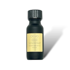 Puede incluir: Una botella de vidrio negro con una etiqueta dorada que dice "DOJO JOSEPHINE JOSEPHINE NOTES ROSE CUMIN VETIVER CEDAR HK GUNAC WOOD OUMNUM AROMATIC DIFFUSER OIL APPROX 15 ML"