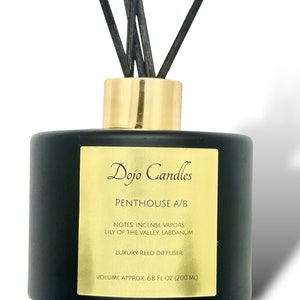 Könnte beinhalten: Schwarze Glasdiffusor-Flasche mit goldenem Deckel und schwarzen Ruten. Das Etikett lautet "Dojo Candles Penthouse A/B Notes: Incense Vapors, Lily of the Valley, Labdanum Luxury Reed Diffuser Volume Approx. 6.8 fl oz (200 ml)"