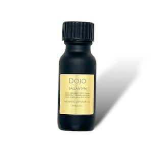 May include: A black glass bottle with a gold label that reads "DOJO BALLANTYNE AROMATIC DIFFUSER OIL APPROX 10 ML". The label lists notes of bergamot, petit grain, grapefruit, orange blossom, cedar, amber, musk, and vetiver.