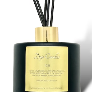 May include: Black glass reed diffuser bottle with a gold lid and black reeds. The label is gold with the text "Dojo Candles 1031" and a list of fragrance notes: Lavender, Clary Sage, Vanilla, Bitter Almond, Orris, Cashmeran, Leather, Amber, Tonka Beans. The label also says "Luxury Reed Diffuser" and "Volume Approx. 6.8 fl oz (200 ml)".