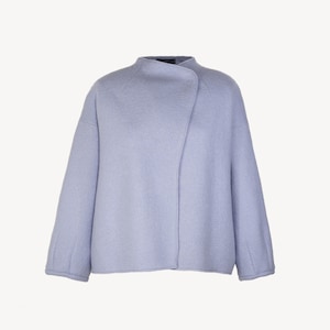 Puede incluir: Una chaqueta de color azul claro, de manga larga, de gran tamaño, con cuello y cierre de un solo botón.