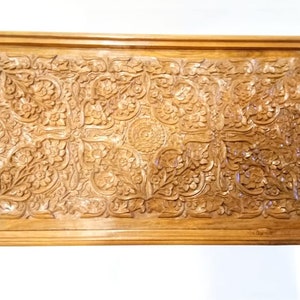 May include: A wooden tray with intricate carved floral designs. The tray is rectangular and has a dark brown finish.