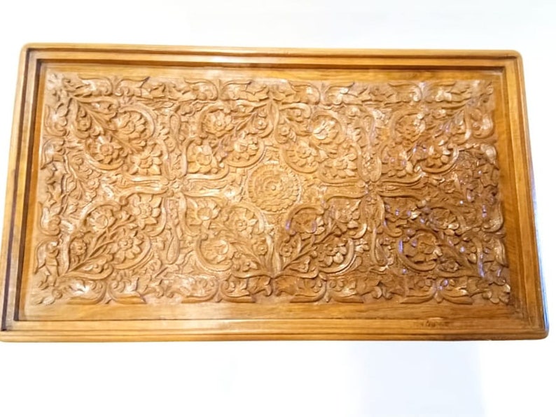 May include: A wooden tray with intricate carved floral designs. The tray is rectangular and has a dark brown finish.