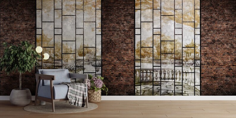 Może przedstawiać: Wnętrze salonu z ceglaną ścianą, na kt&oacute;rej znajduje się tapeta z czarnym wzorem siatki i wyblakłym obrazem sceny ogrodowej. Przed ścianą stoi niebieski fotel z pledową narzutą. W pokoju znajduje się r&oacute;wnież doniczkowa roślina i lampa stojąca.