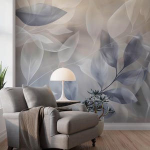 Könnte beinhalten: Ein grauer Sessel mit einer braunen Decke steht vor einer Wandmalerei mit großen, abstrakten Blättern in Grau- und Blautönen. Eine weiße Lampe und eine Topfpflanze stehen auf einem Beistelltisch. Der Raum hat eine moderne, minimalistische Ästhetik.