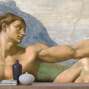 May include: A close-up of a painting depicting a muscular man with his arm outstretched. The man is nude and has a light brown complexion. The background is a light blue sky with a large, rocky mountain in the distance.