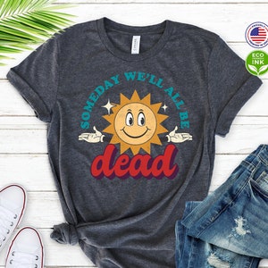 May include: A dark heather grey t-shirt with a retro sun graphic and the text "Someday we'll all be dead".