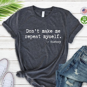 May include: A dark heather grey t-shirt with the text "Don't make me repeat myself. - History" printed in white.