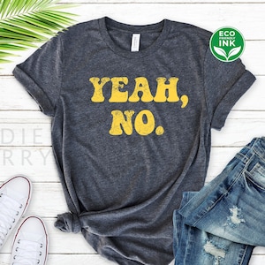 May include: A dark grey t-shirt with the text "Yeah, No." printed in yellow. The shirt is made of a soft, comfortable material and has a relaxed fit.