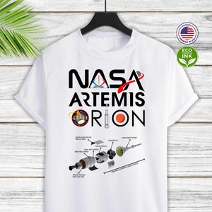 May include: White t-shirt with a black graphic design featuring the NASA logo, the words "Artemis Orion", and a diagram of the Orion spacecraft.