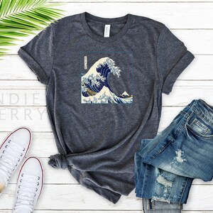 Op de afbeelding: Een donker grijs t-shirt met een grafische print van de Grote Golf voor Kanagawa, een beroemde Japanse houtsnede van Hokusai.