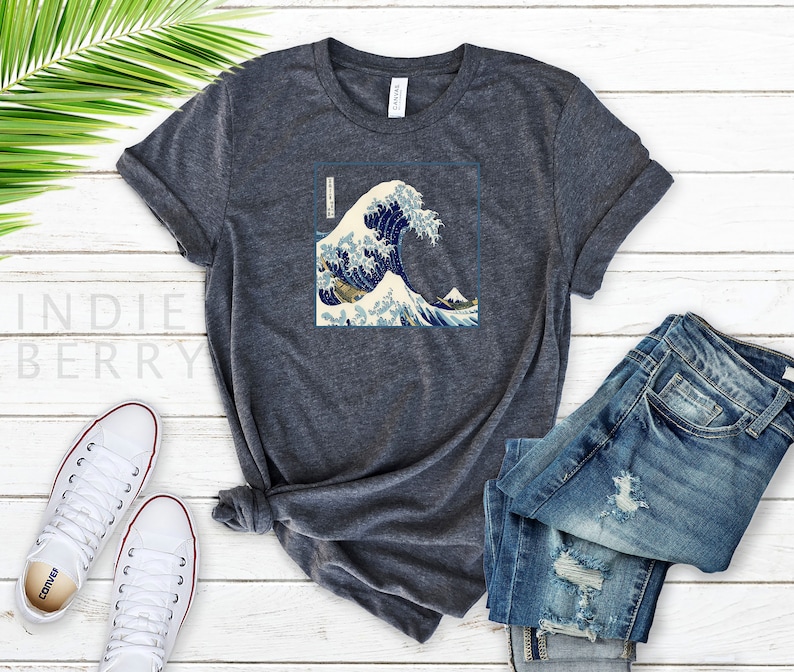 Op de afbeelding: Een donker grijs t-shirt met een grafische print van de Grote Golf voor Kanagawa, een beroemde Japanse houtsnede van Hokusai.