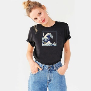 Op de afbeelding: Een zwart T-shirt met een grafische print van een blauwe golf. De golf is een traditioneel Japans kunstontwerp.