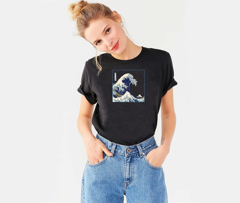 Op de afbeelding: Een zwart T-shirt met een grafische print van een blauwe golf. De golf is een traditioneel Japans kunstontwerp.