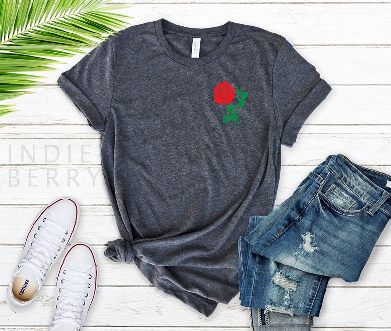 May include: A dark gray t-shirt with a red rose embroidered on the left chest. The rose has green leaves and a stem.