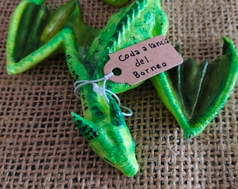 Puede incluir: Una figurita de dragón verde con cola enroscada y alas. La figurita está hecha de un material texturizado y tiene una etiqueta que dice "Coda a lancia del Borneo".
