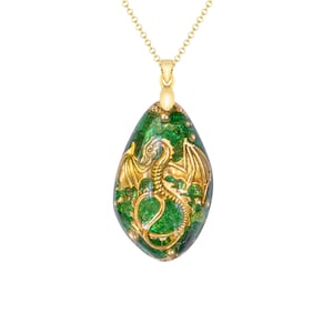Könnte beinhalten: Eine goldene Kettenkette mit einem grünen und goldenen Anhänger mit einem Drachenmotiv. Der Anhänger ist tropfenförmig.