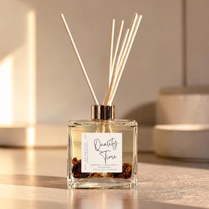 May include: A square glass reed diffuser bottle with a gold cap and six wooden reeds. The white label reads Quality Time, Jasmine, Palo Santo, Patchouli, and 8oz (226g) Diffuser. Dried botanicals are visible at the bottom of the clear liquid.