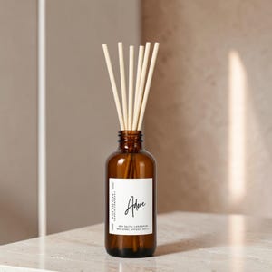 May include: An amber glass diffuser bottle with six light-colored reeds. The white label features the text Adore, Wick and Glow Candle Company, and Sea Salt + Cardamom 8oz (236g) Diffuser Refill in black, sans-serif and script typography.
