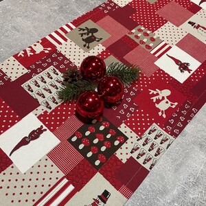 Könnte beinhalten: Ein roter und weißer Weihnachtstischläufer mit Patchwork-Design mit Rentieren, Schneemännern, Pilzen und anderen festlichen Motiven. Der Läufer ist mit roten Punkten und weißen Herzen verziert.