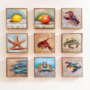 May include: Nine square framed paintings with wooden frames. The paintings depict various subjects, including a lemon, a mango, a lobster, a starfish, a crawfish, a crab, a group of fish, crabs on a beach, and a crab.