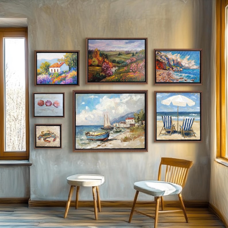 May include: A collection of framed landscape and seascape paintings. The artwork includes scenes of a white house in a field of purple flowers, coastal views, and beach scenes with sailboats and chairs. The paintings are in brown frames and hang on a gray wall.