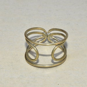 Peut inclure: Un bracelet en métal doré avec un design géométrique simple. Le bracelet est composé de trois bandes entrelacées qui forment une boucle continue.