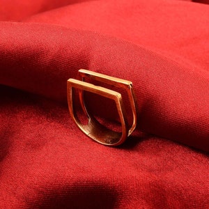 May include: A gold-toned ring with a double-square design. The ring is made of metal and has a simple, modern style.